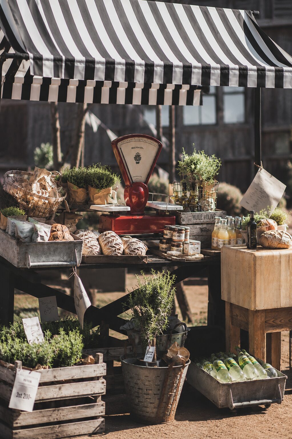 Marktkraam met brood, verse kruiden, olijfolie en streekproducten onder een gestreepte luifel